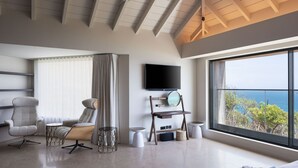 Un dormitorio moderno con un ventanal grande, un televisor de pantalla plana y una silla de madera.