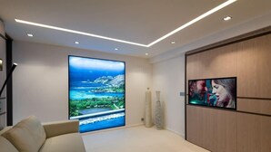 A modern living room with a large TV, a sofa, and a decorative vase.