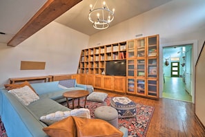 A living room with a sofa, ottomans, a coffee table, a TV, and a bookshelf. - Bohemian Home w/ Screened Porch, 3 Mi to Lake! (Stillwater)