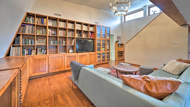 Un salón amplio con una gran estantería, televisor, sofá y techo de madera.