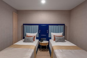 Une chambre d’hôtel avec deux lits, une petite table ronde et une armoire bleue.