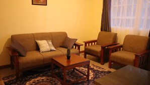 Un salon comprenant un canapé, deux fauteuils, une table basse et un tapis à motifs.