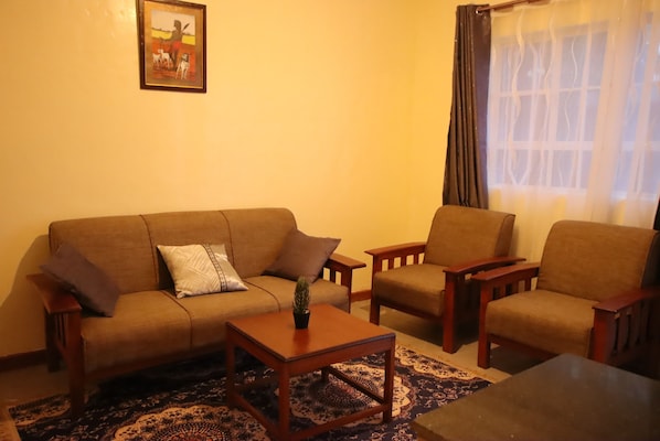 A living room with a sofa, two armchairs, a coffee table, and a patterned rug.