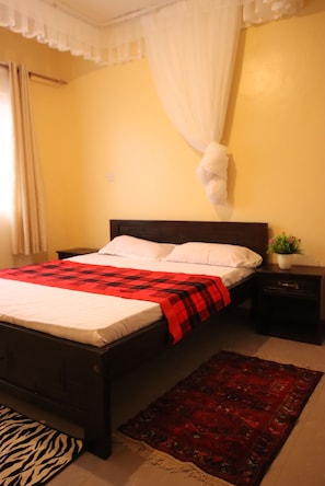 A bed with a red and black checkered blanket, a white pillow, and a white canopy.