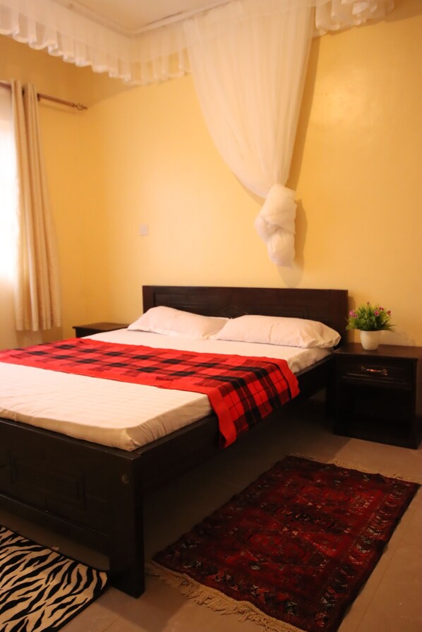 A bed with a red and black checkered blanket, a white pillow, and a white canopy. - Stay.Plus Ebony Mara House (Narok)