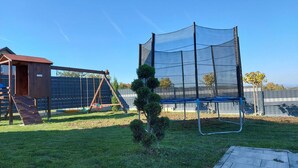 A backyard with a swing set, a trampoline, and a small tree. - Holiday Home Gračec (Brckovljani)