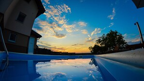 A swimming pool with a sunset view, a building with windows, and a tree. - Holiday Home Gračec (Brckovljani)