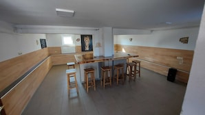 A modern kitchen with a wooden bar area, stools, and a lion painting on the wall. - Holiday Home Gračec (Brckovljani)