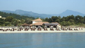 A beachfront hotel with multiple lounge areas and a building with a red roof.