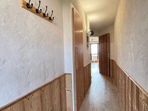 A hallway with wooden paneling, a coat rack, and a door leading to a balcony.