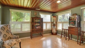 A room with wooden ceiling, a vintage radio, a television, and a patterned armchair. - Riverfront Getaway w/ Hot Tub & Game Room! (New Port Richey)