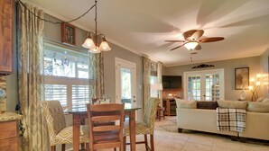A dining area with a wooden table and chairs, a ceiling fan, and a view of the living room. - Riverfront Getaway w/ Hot Tub & Game Room! (New Port Richey)