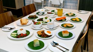 A dining table set with various dishes, including rice, vegetables, and meat, in a restaurant setting. - JPOD Capsule Hotel (Kota Kinabalu)