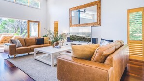Ein geräumiges Wohnzimmer mit Ledersofas, einem Couchtisch und einem großen Spiegel.