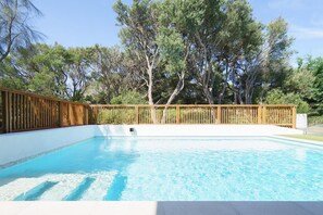 A rectangular swimming pool with clear blue water, surrounded by a wooden fence and trees. - The Salt House - Poolside amongst the Moonah Trees (Rye)