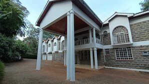 A two-story building with a covered entrance, stone walls, and multiple windows. - Stay.Plus karen Party House (Nairobi)