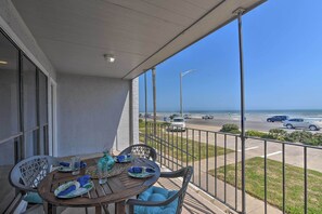 Ein Balkon mit Tisch für Zwei, mit Blick auf einen Parkplatz und den Ozean.