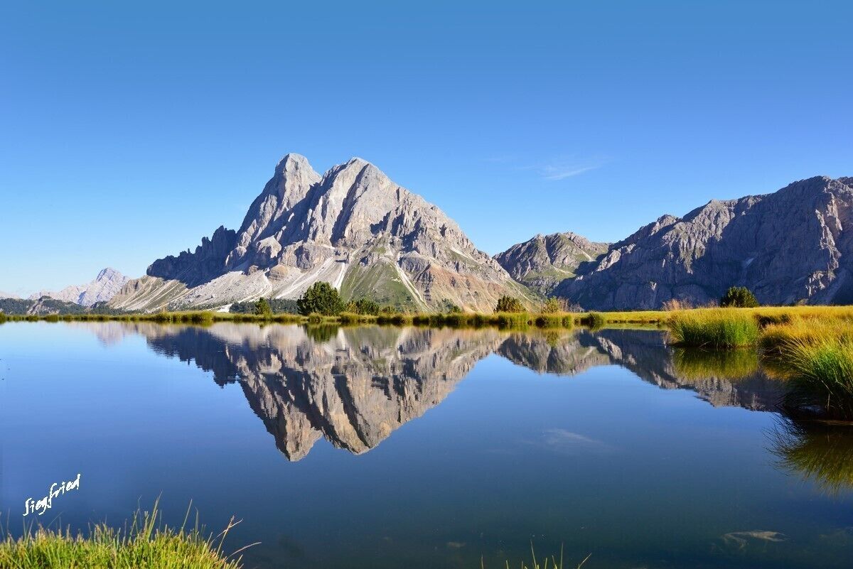 Uma montanha refletida em um lago calmo sob céus claros.
