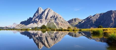 Uma montanha refletida em um lago calmo sob céus claros.