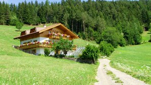 Un chalet à deux étages doté d’un balcon, situé au milieu d’une colline boisée.