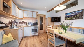 Une cuisine compacte avec des meubles en bois, un four encastré et un coin repas comprenant une table et des chaises.