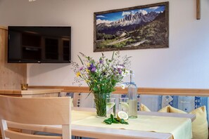 A dining area with a table set for two, a vase of flowers, and a bottle of water.