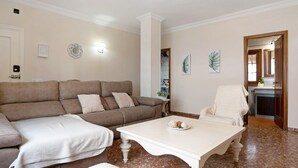 A living room with a beige sofa, a white coffee table, and a white armchair.
