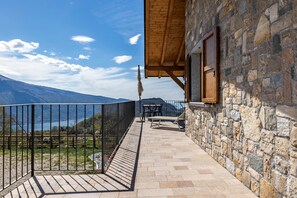 Ein Balkon mit Steinwand, Holzboden und Blick auf Berg und See.