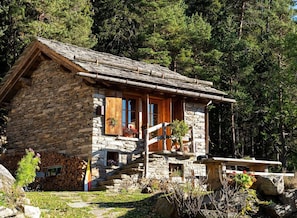 A stone house with a wooden porch, a small window, and a flag.