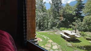 A room with a window overlooking a garden with a picnic table and a stone pathway.