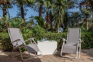 Deux fauteuils confortables, une petite table et un globe décoratif, le tout installé dans un jardin.
