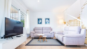 En moderne stue med et fladskærms-tv, to sofaer, et sofabord og kunst på væggen.