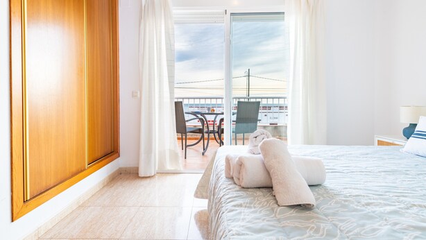Et hotelværelse med seng, balkon med bord og stole samt udsigt til himlen.