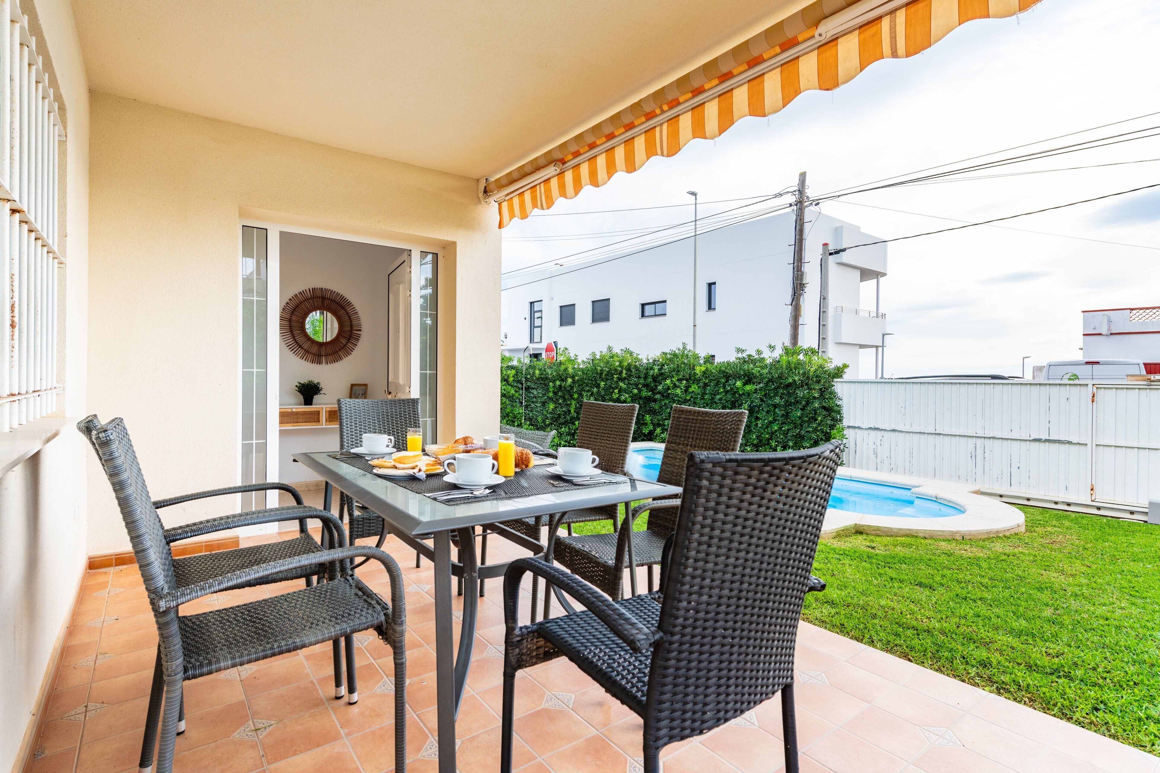 Una veranda esterna con tavolo e sedie, una piccola piscina e un recinto bianco.