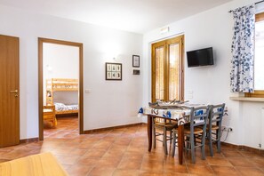 A room with a bed, a table with chairs, a television, and a window with curtains. - Agriturismo 'Trilo Begonia' with Pool, Wi-Fi & Garden (Marina di Grosseto)