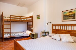 Ein Zimmer mit Etagenbetten, einem kleinen Tisch mit Lampe und einem Bild an der Wand.