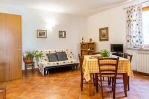 Un salon confortable avec un canapé, une table à manger et des chaises, un téléviseur et une plante en pot.