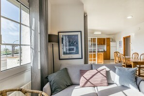 Una sala de estar moderna con un sofá, un cuadro enmarcado y vistas al área de la cocina y el comedor.