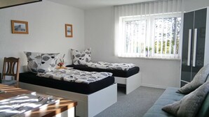 A modern bedroom with a bed, a desk, and a window with blinds.