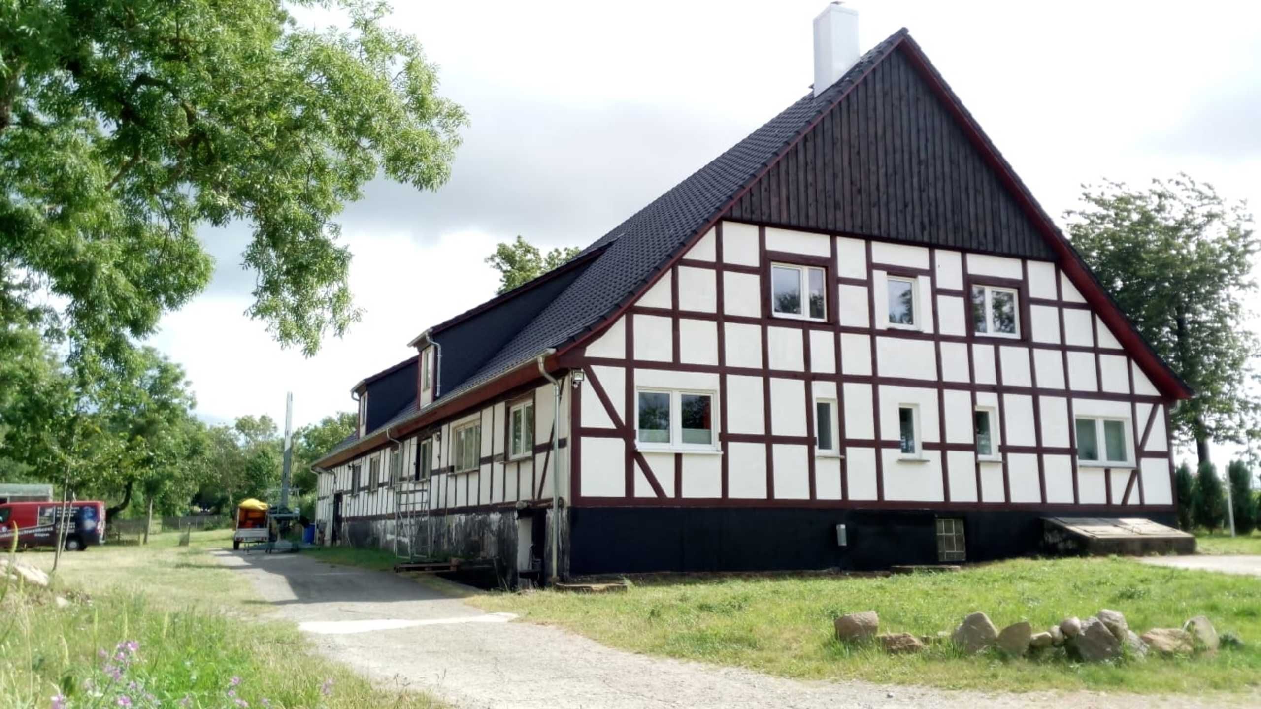 Uma casa tradicional em estilo de enxaimel, com telhado em duas águas íngreme, chaminé e pequeno alpendre.