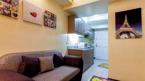 A living room with a sofa, a coffee table with a flower arrangement, and a kitchen in the background. - Couple's Getaway|Netflix|Fast net|Parking nr MAKTI (Mandaluyong)