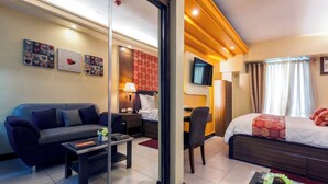 A hotel room with a sofa, a desk, a bed, and a TV. - Couple's Getaway|Netflix|Fast net|Parking nr MAKTI (Mandaluyong)