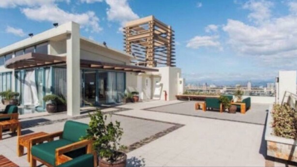 A rooftop terrace with outdoor seating, a modern building, and a view of the cityscape. - Couple's Getaway|Netflix|Fast net|Parking nr MAKTI (Mandaluyong)