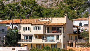Un immeuble à plusieurs étages, doté de balcons, d’un toit en tuiles et surplombant un paysage montagneux.