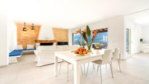 Un salon moderne avec une cheminée, une table à manger avec des chaises et une vue sur la ville.
