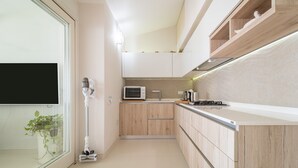 Eine moderne Küche mit Holzausstattung, einer Mikrowelle, einem Herd und einem Fenster mit Pflanze.