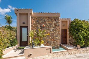 Un bâtiment moderne avec une façade en pierre, une porte et un petit espace piscine.