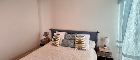 A bedroom with a bed, bedside tables, a lamp, and a window with curtains.