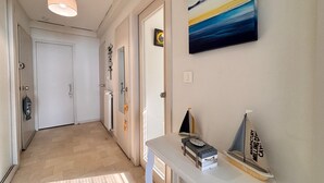 A hallway with a light fixture, a door, a mirror, and a wall-mounted painting. - Beachfront Apartment with Balcony, Sleeps 4, 2 Stars (Les Sables-d'Olonne)