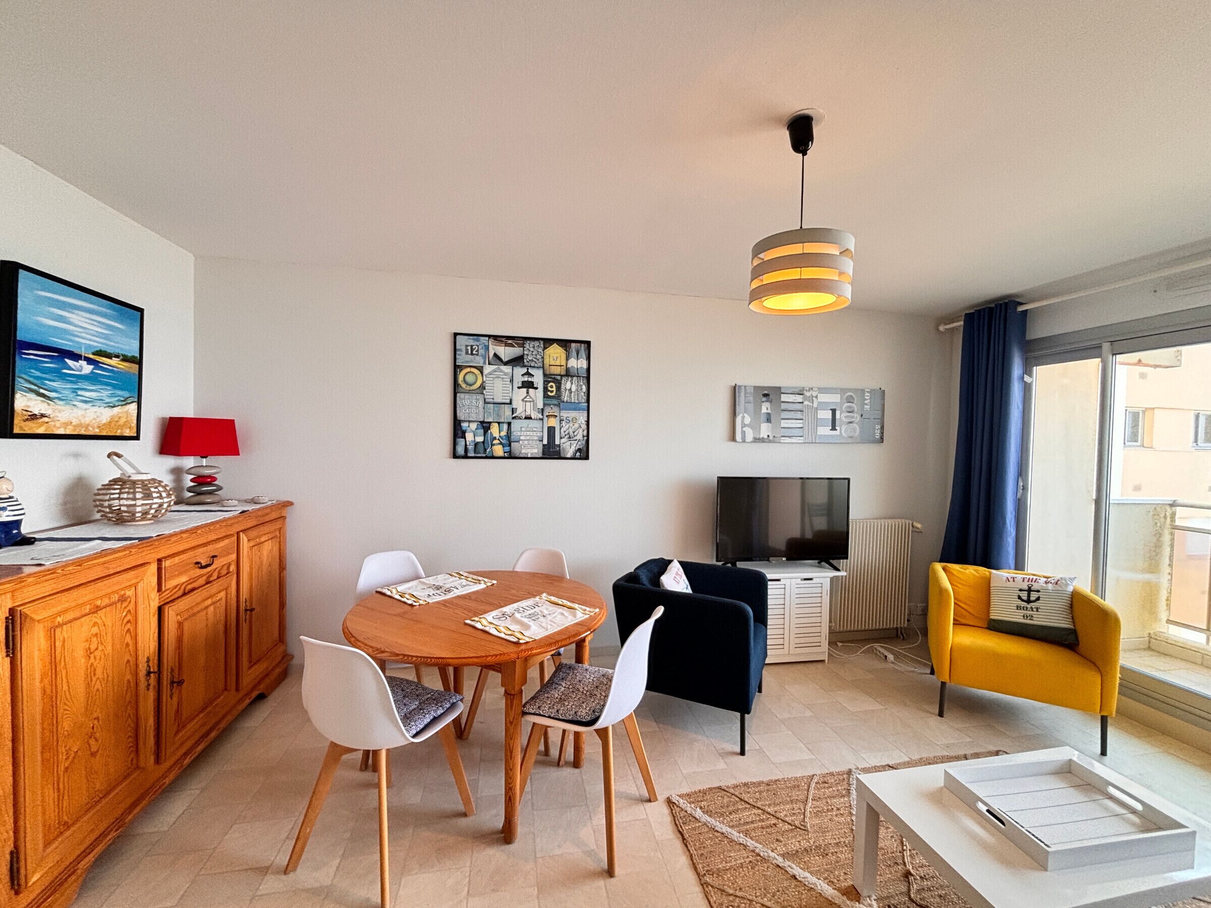 A modern living room with a dining table, chairs, a TV, and a sofa.